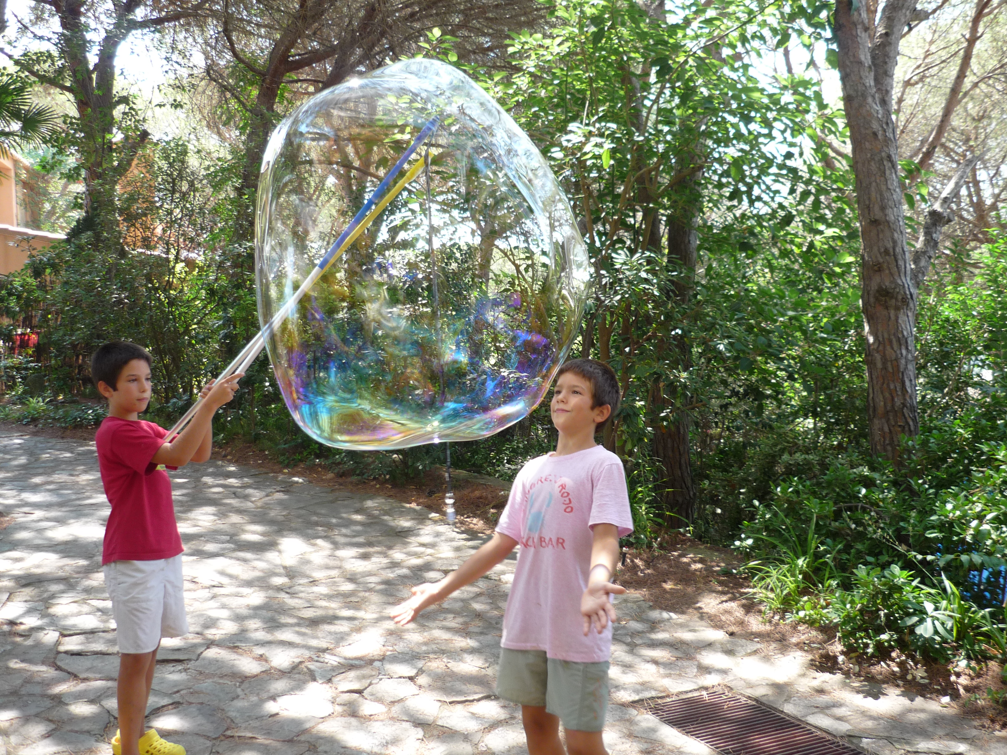 My children blowing giant soap bubbles during summer